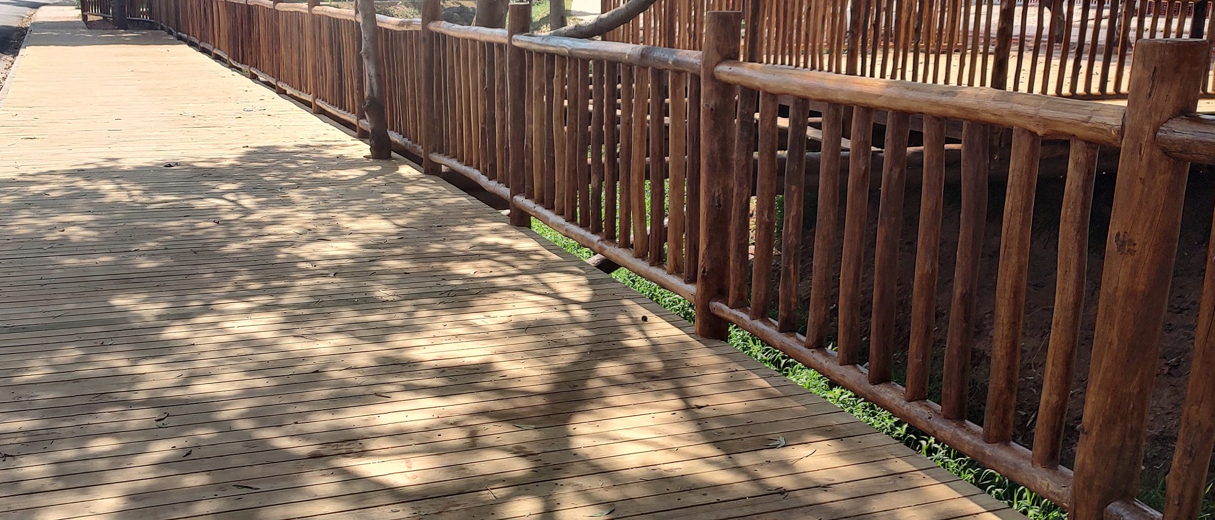 Deck de réguas de pinus tratado com guarda-corpo de toras de eucalipto e sombra de árvores sobre o piso