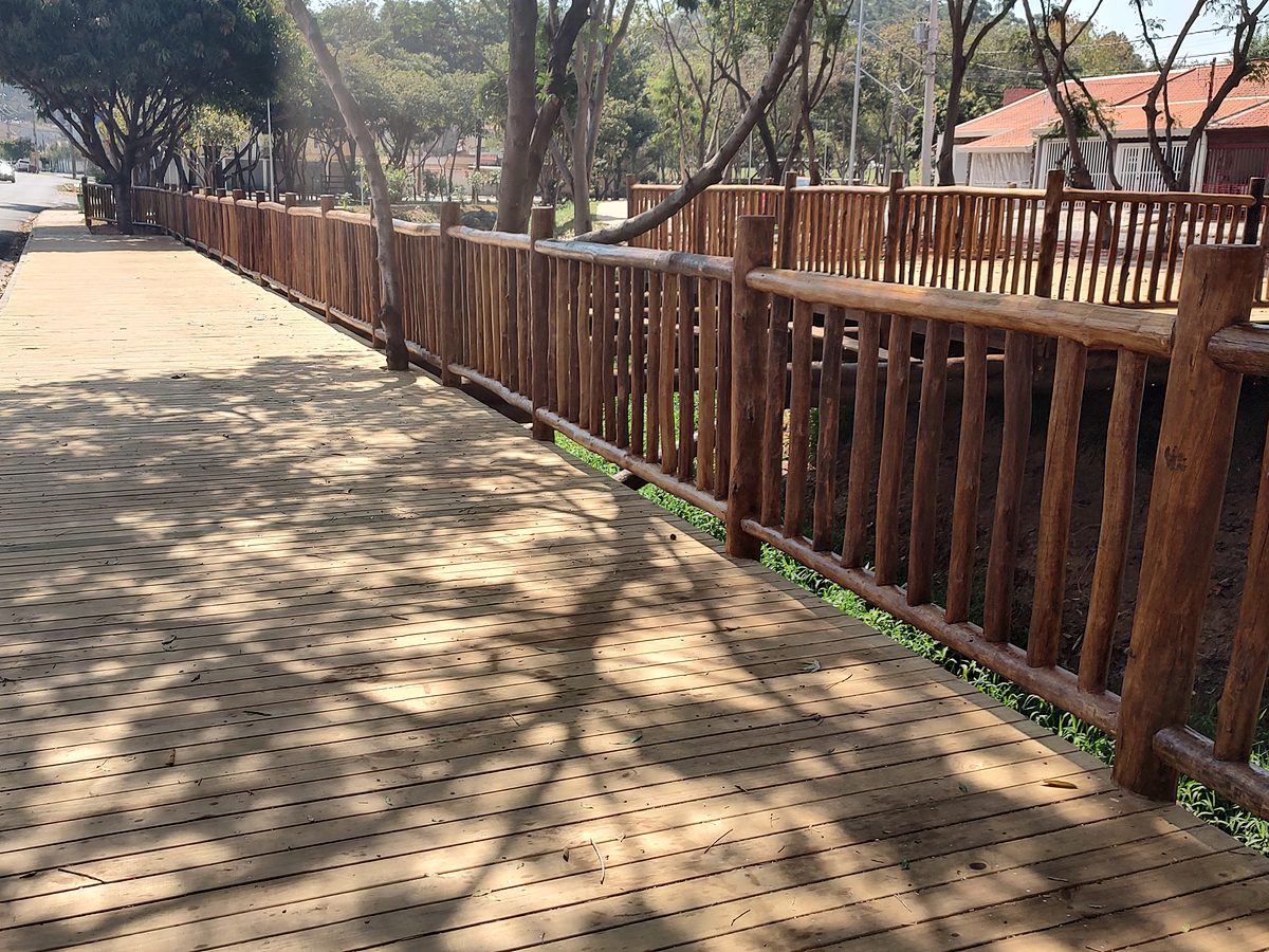 Deck de réguas de pinus tratado com guarda-corpo de toras de eucalipto e sombra de árvores sobre o piso