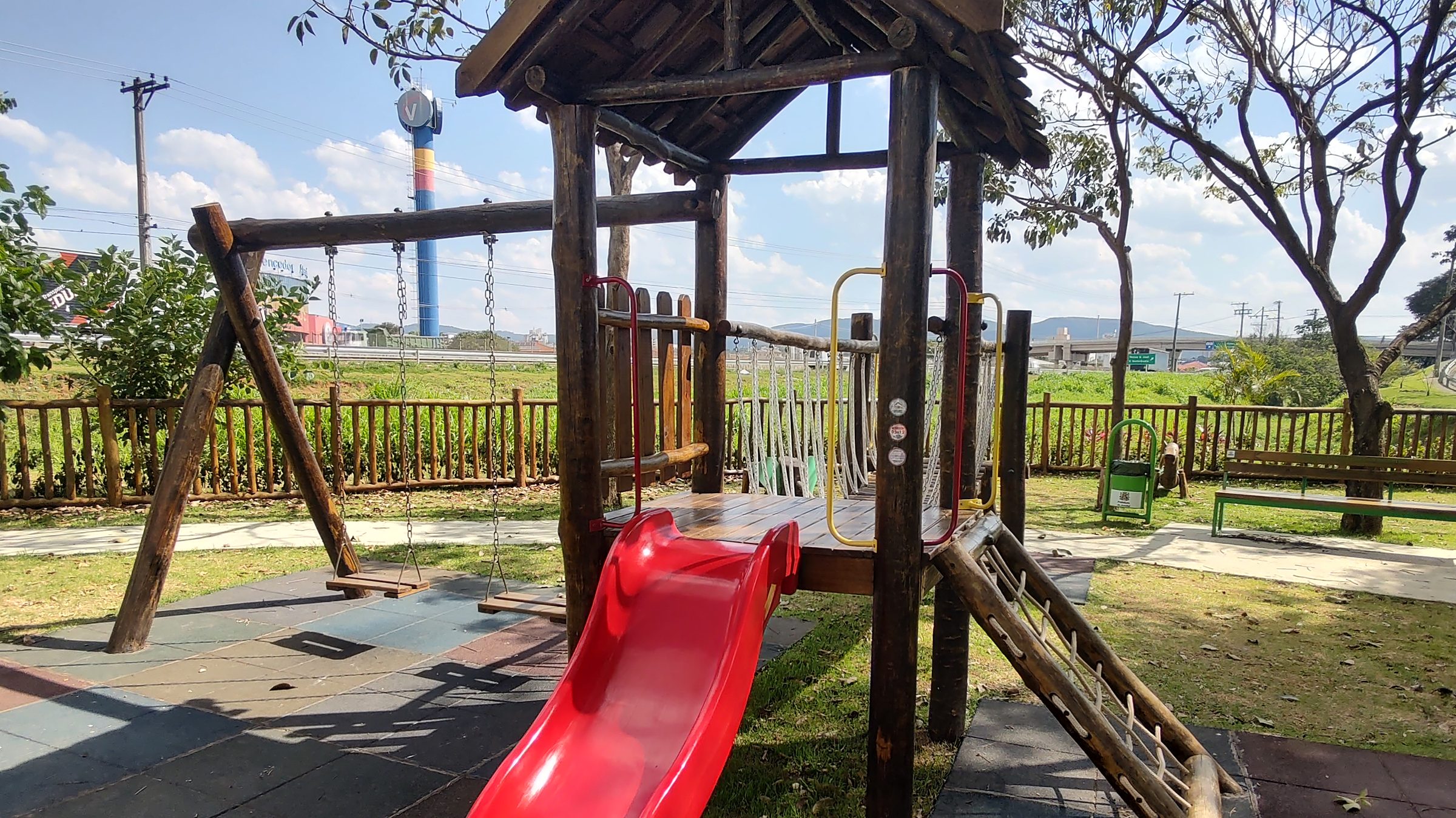 Playground em toras de eucalipto com torre e escorregador vermelho